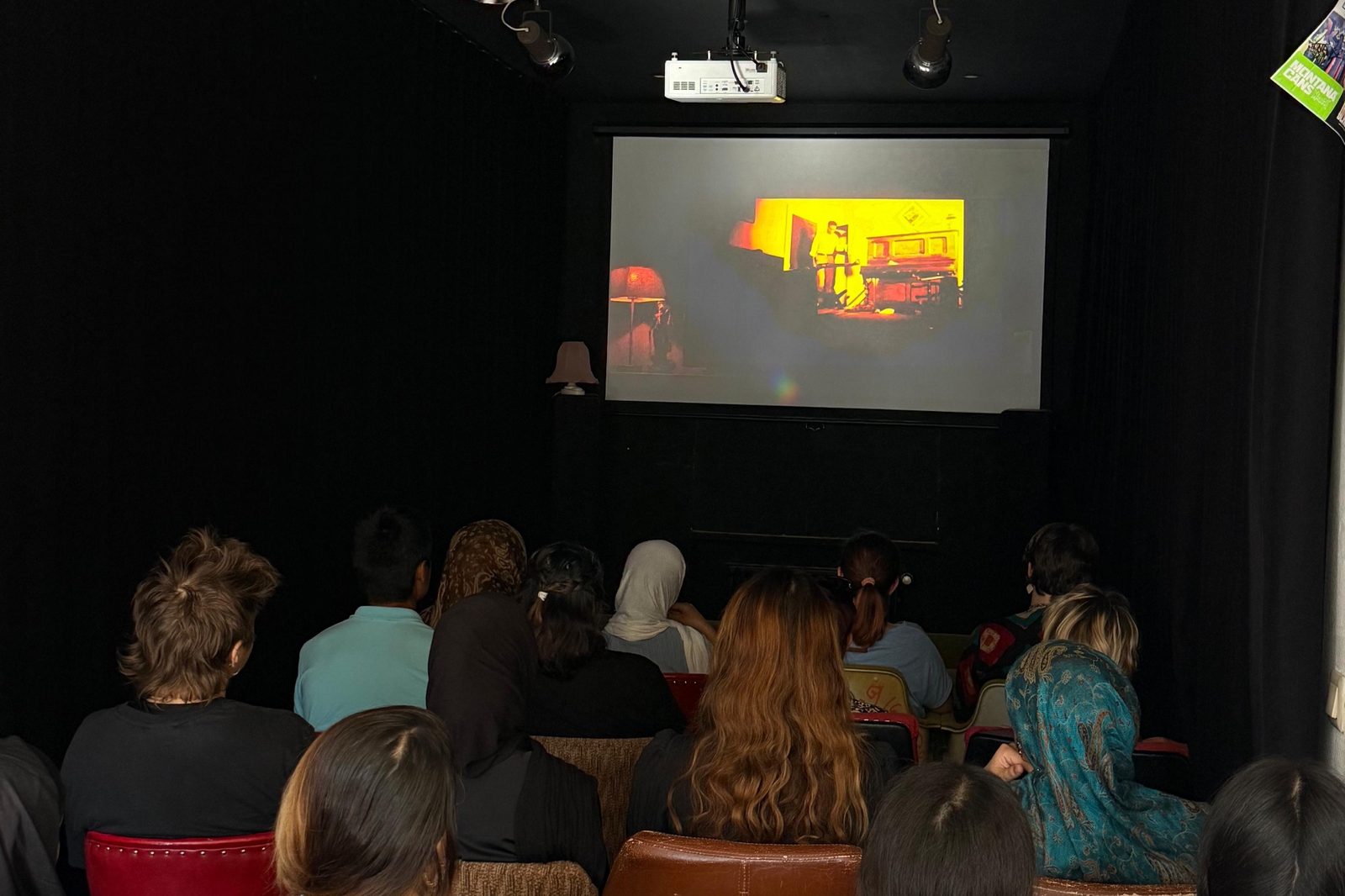 Publikum in bunten Kinosesseln verfolgt den Film „Es brennt“ auf der Leinwand