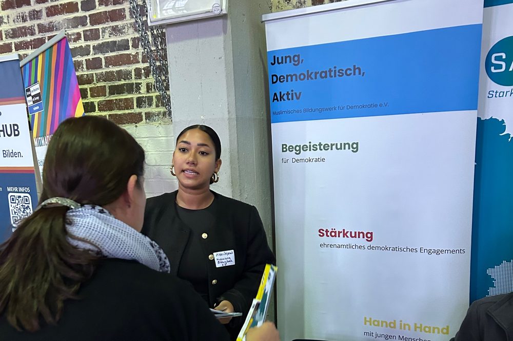 Eine Mitarbeiterin erklärt einer Besucherin am Stand die Projekte