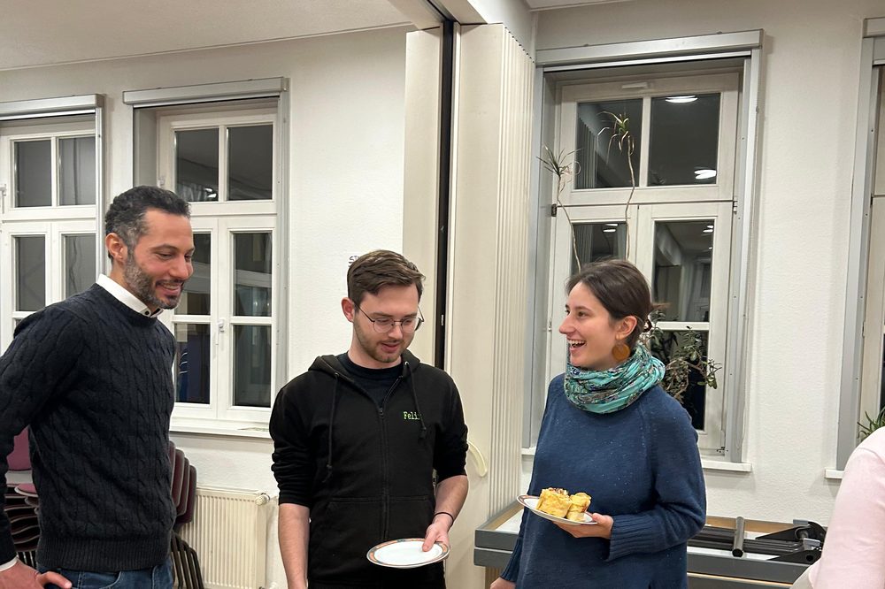 Drei Gäste im Gespräch mit ihren Tellern in der Hand