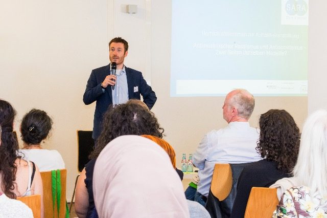 Ein Referent spricht mit Mikrofon zum Publikum