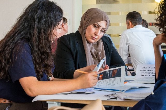 Zwei Teilnehmerinnen lesen beim World-Café gemeinsam Materialien