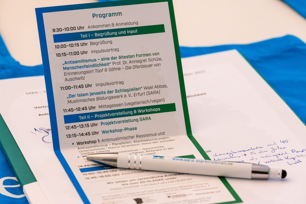 Das Programmheft des Fachtags mit einem SARA-Kugelschreiber