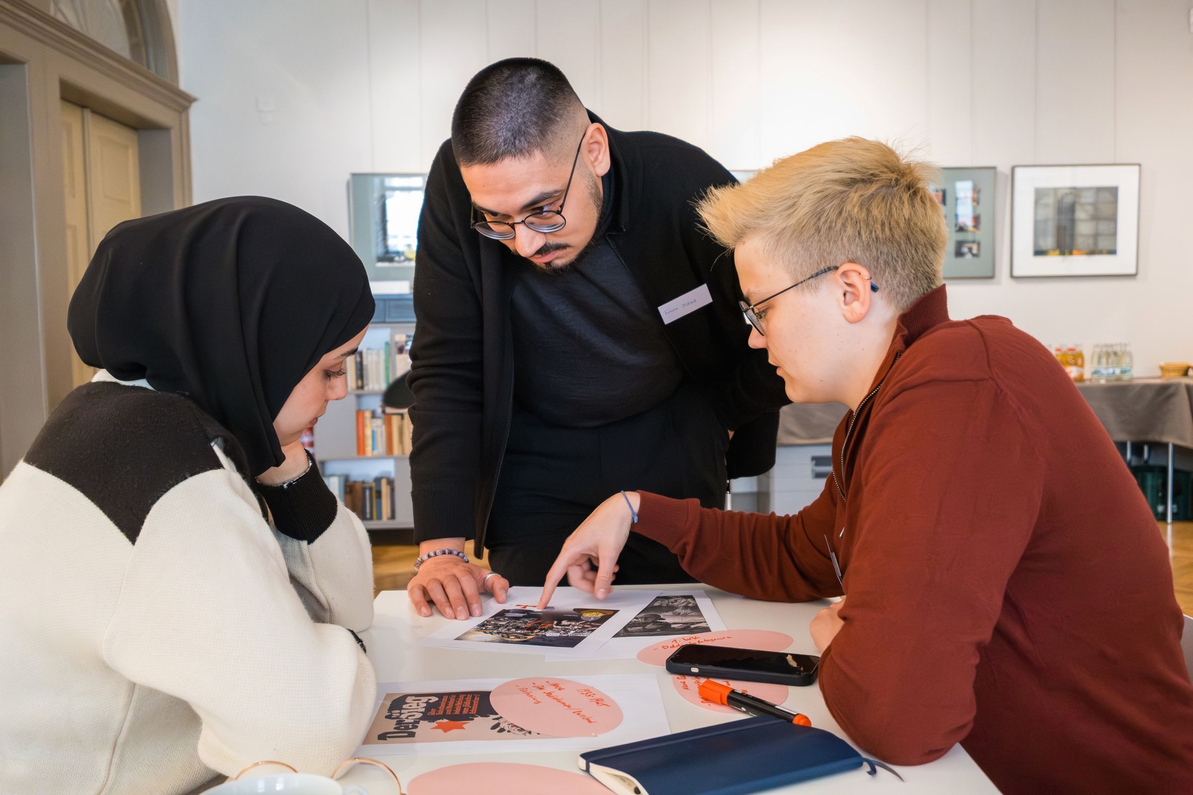 Zwei Teilnehmende analysieren mit einem Referenten historische Bildquellen